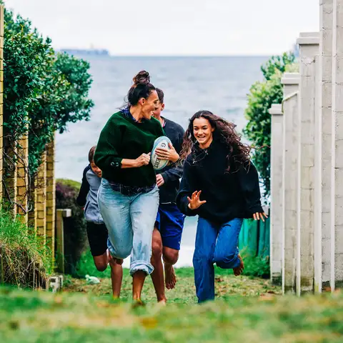 Group running coastal path holding rugby ball