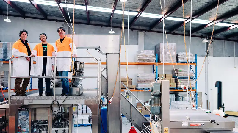 3 men standing on a machinery platform in a warehouse