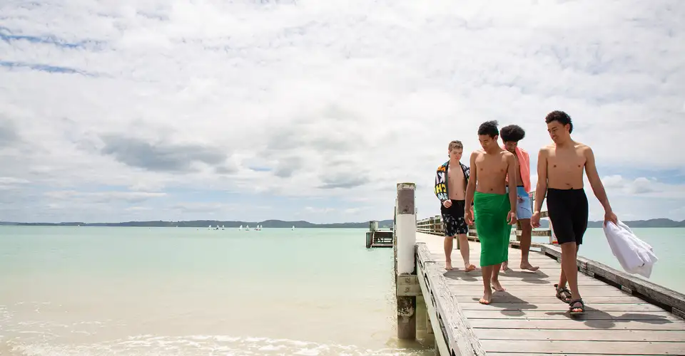 People walk along wooden wharf over calm sea