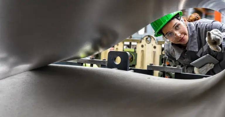 Factory worker inspecting machinery in industrial setting