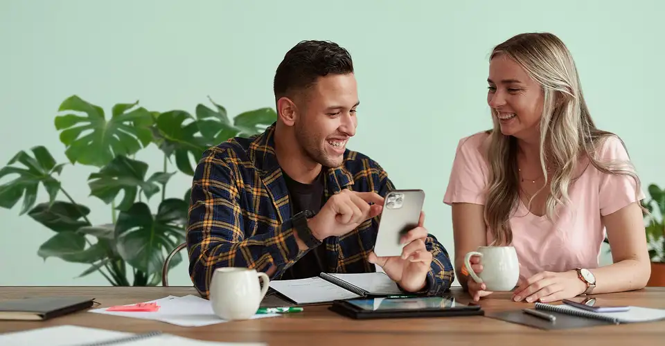 Two people look at mobile phone at table indoors