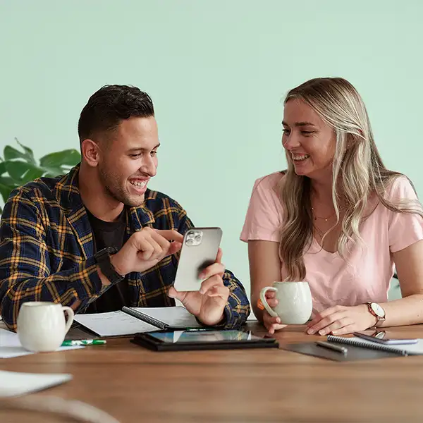 Two people look at mobile phone at table indoors