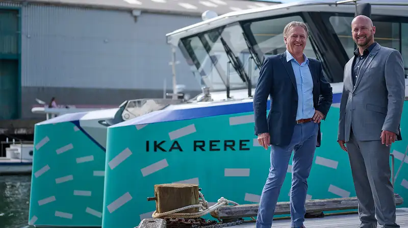 Men in suits next to an electric ferry