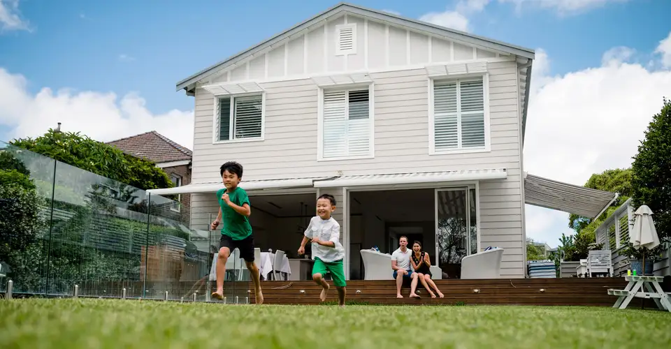 Children running across lawn in front of house