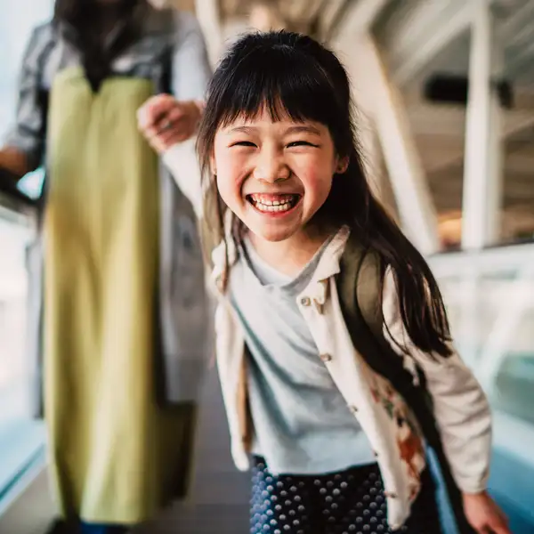 Child walking on travelator smiling with adult behind