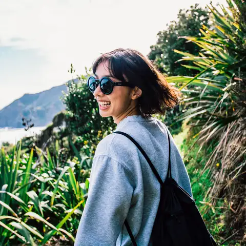 Person looking back walking coastal track sunny