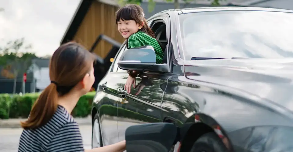 Person charging electric car beside passenger at window