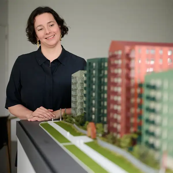 A person standing beside a detailed model of modern apartment buildings.