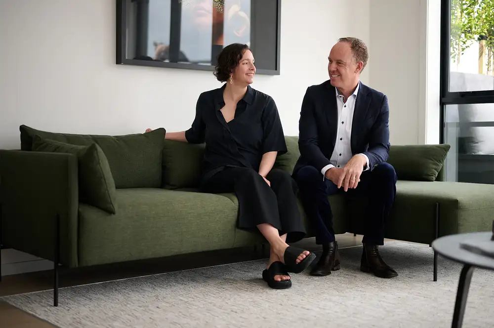Two people sitting on a green sofa in a modern living room.