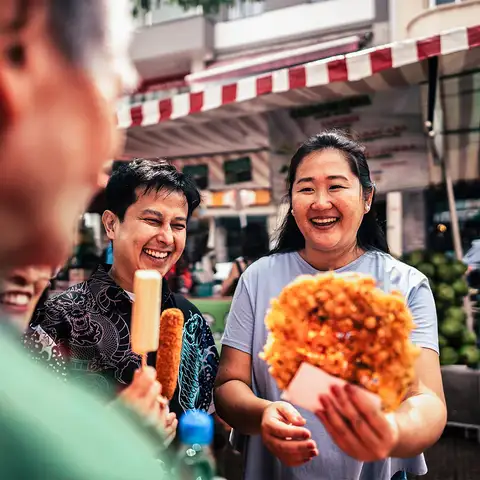 Group of people share street food at outdoor market smiling close-up