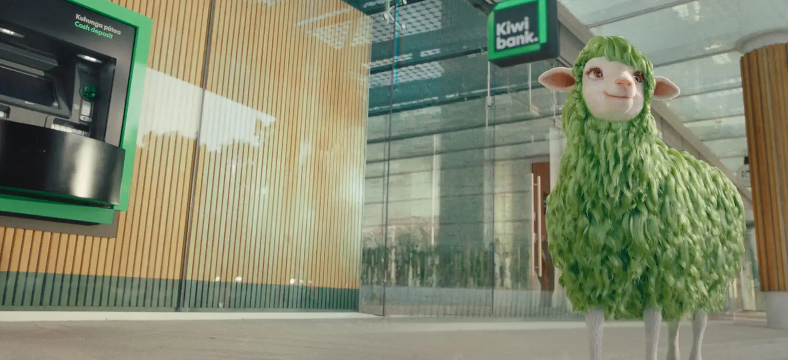 'Buck' the green sheep stands outside a Kiwibank branch on a sunny day