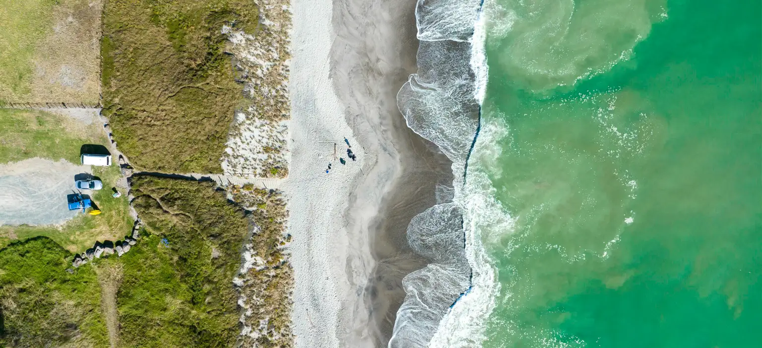 Coastline curves along sandy beach beside turquoise ocean aerial view