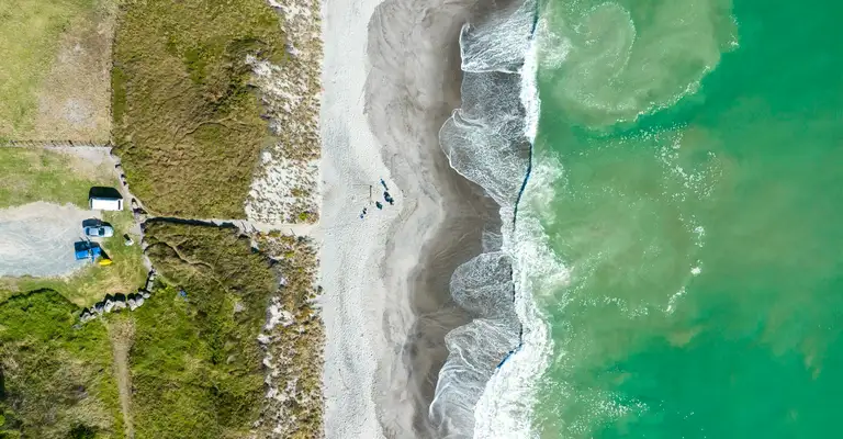 Coastline curves along sandy beach beside turquoise ocean aerial view