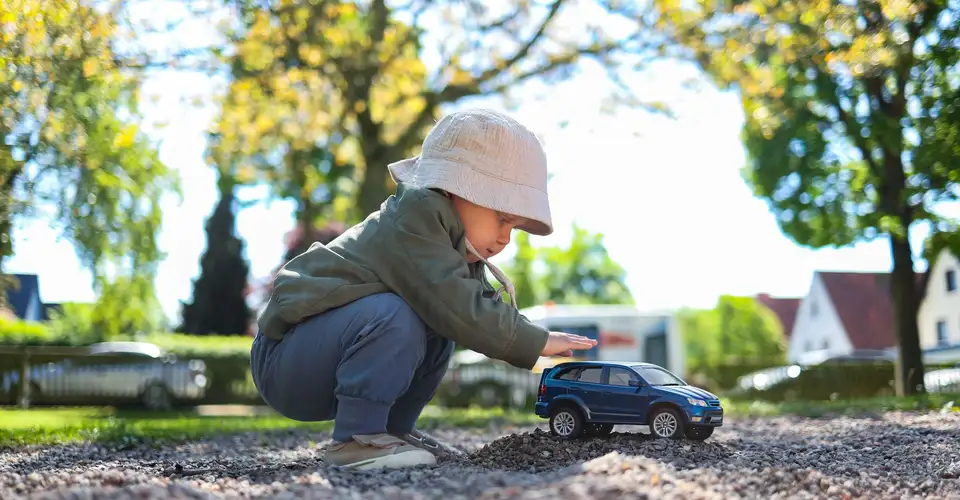 A child playing with a car outside house