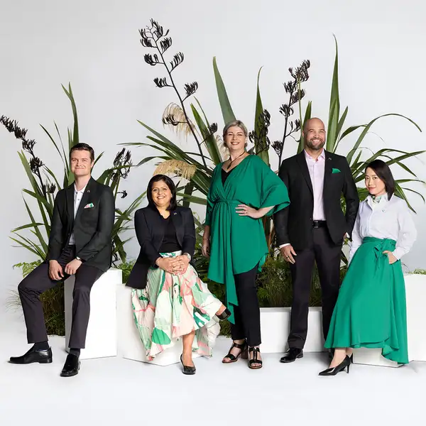 Five people standing and sitting among native plants in studio