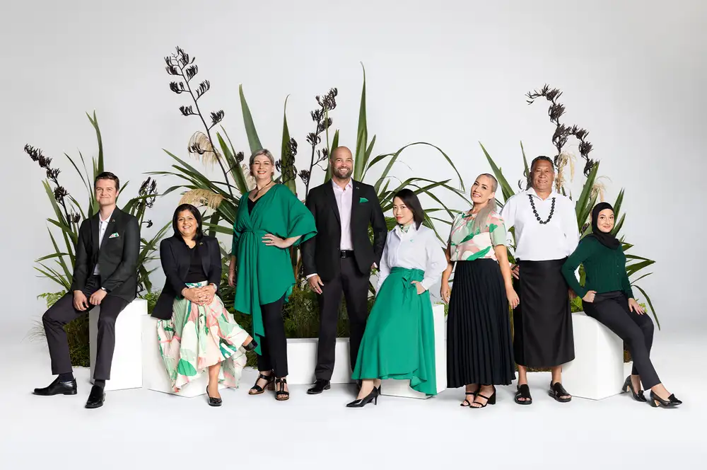 Eight people standing and sitting among native plants in studio