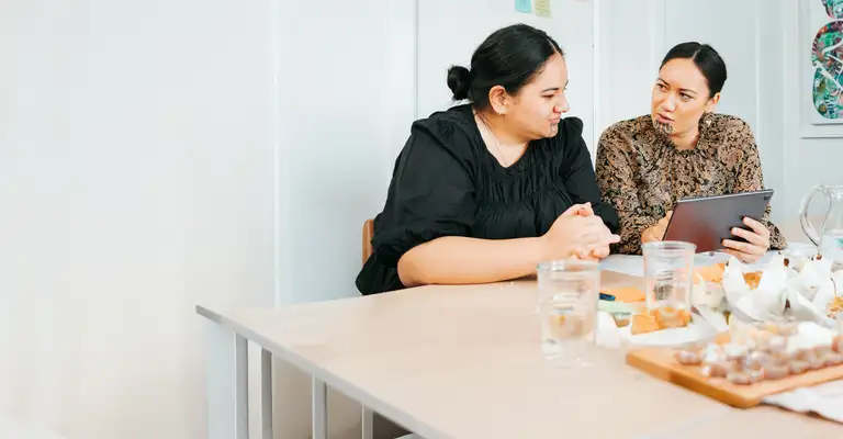 Two people discussing over tablet at dining table