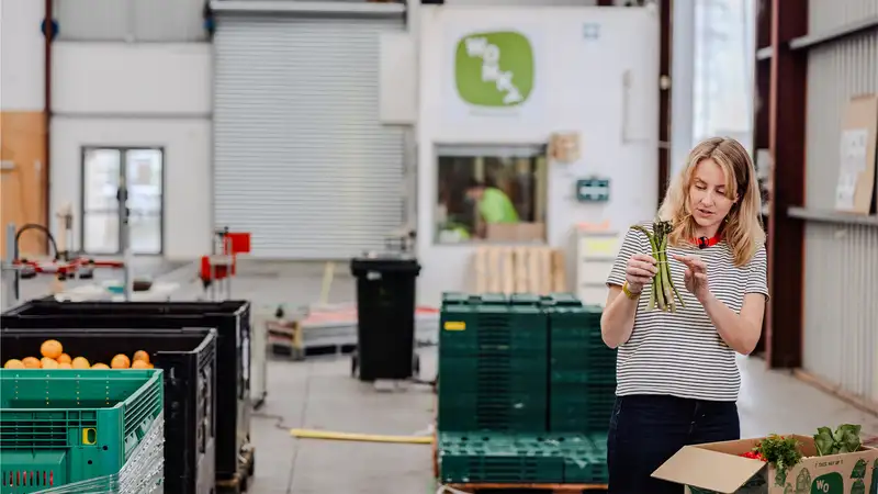 Woman holds a bundle of asparagus in a warehouse