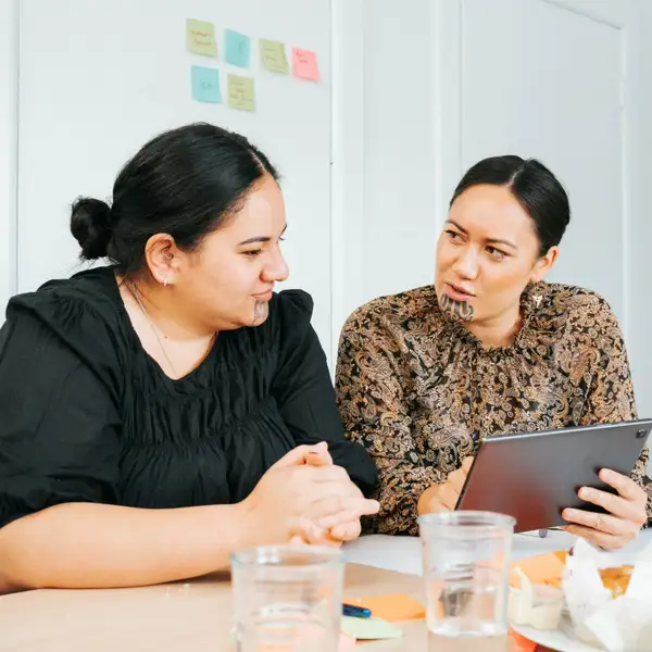 Two people discussing over tablet at dining table
